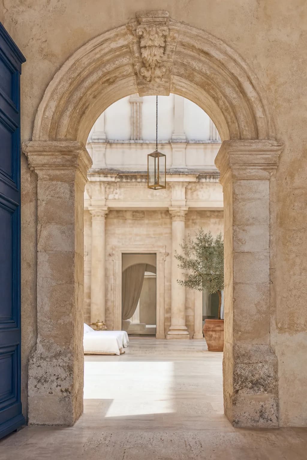 Breakfast laid on a small table in the courtyard, morning sun on one column and deep shade under the loggia